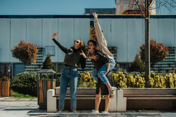 Curly haired girl taking a selfie with her brunette female friends. Smiley brunette girl giving...