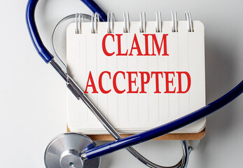 CLAIM ACCEPTED word on notebook with medical equipment on background