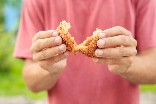 A guy's hand holds sweet pastry with jam, snack and fast food concept. Selective focus on hands with blurred background