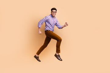 Fototapeta na wymiar Full length photo of cheerful nice crazy man wear trendy clothes running empty space isolated on beige color background