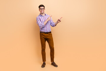 Fototapeta premium Full length photo of satisfied positive man wear stylish clothes demonstarte empty space look up poster isolated on beige color background