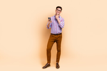 Fototapeta na wymiar Full length photo of attractive nice man wear trendy clothes look up empty space advert banner isolated on beige color background