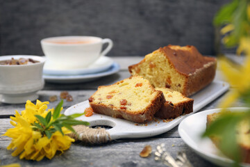 Summer dessert. Raisin cake, cup of tea and bouquet of forsythia