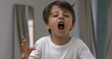 Angry child yelling and screaming at camera in super slow-motion. Upset male caucasian kid in...
