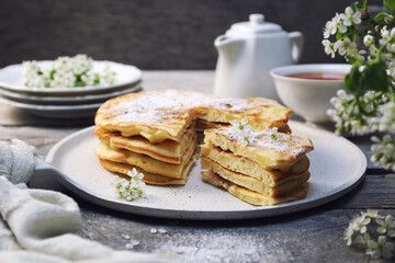 French cuisine. Matefaim. Stack of sweet Apple Pancakes, cup of tea and white spring flowers - 668701194