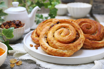 French roll raisin buns, teapot and cup of tea for sweet breakfast - 668701314