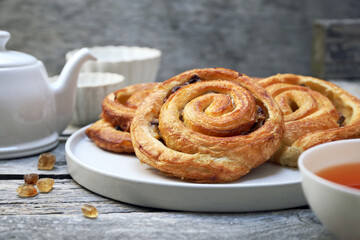 French roll raisin buns, teapot and cup of tea for sweet breakfast - 668701393