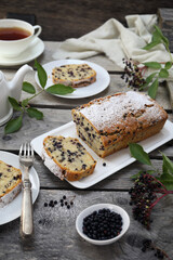 Summer baking. Black elderberry cake, teapot and cup of tea for summer tea party - 668701516