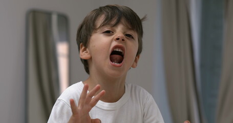 Angry child yelling and screaming at camera in super slow-motion. Upset male caucasian kid in tantrum mode - Powered by Adobe
