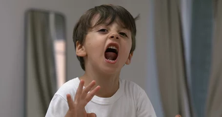 Fotobehang Angry child yelling and screaming at camera in super slow-motion. Upset male caucasian kid in tantrum mode © Marco