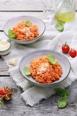 Italian cuisine. Plate of tomato risotto, olive oil, basil and cherry tomatoes, two servings - 668701913