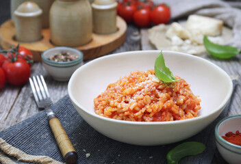 Italian cuisine. Plate of tomato risotto, olive oil, basil and cherry tomatoes - 668701953