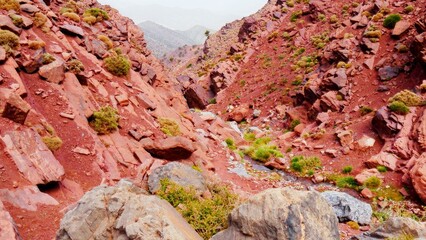 Les gorges tizi N'Ghougoult Atlas maroc, avec des rochers et sa terre rouge, sa peu de végétation, ruisseau d'eau, parcours sportif, beauté naturelle, exploration à l'inconnu, pente raide de montagne,