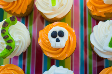 Decorated cupcakes in a Halloween theme.  Orange frosting with an skull decoration on top.