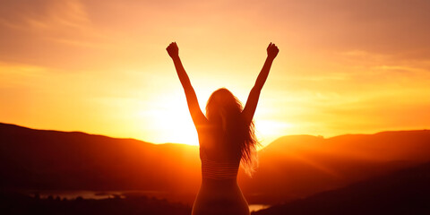Silhouette of woman with arms raised up in beautiful sunset landscape
