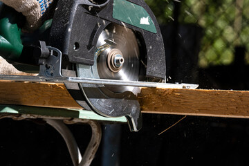 The use of a manual circular saw in woodworking. A man using a circular saw saws boards.