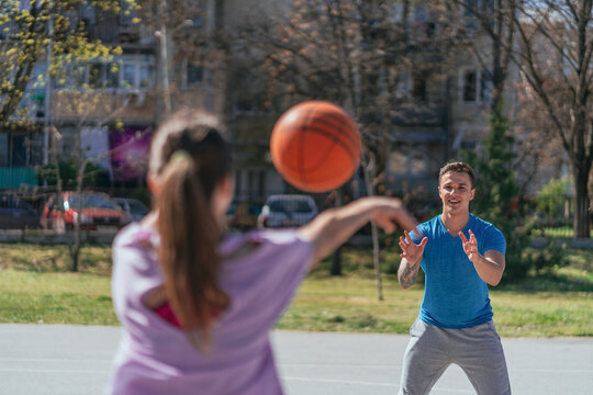 Back view shot of girl throwing basketball ball to her boyfriend