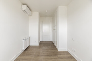 Empty room with air conditioning unit, built-in wardrobes with white wooden doors matching the...