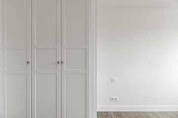 Empty room with fitted wardrobes with white wooden doors with access door and matching baseboards