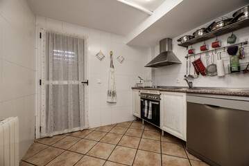 Kitchen furnished with integrated stainless steel appliances and exit door to a drying terrace