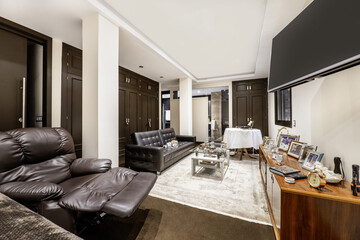 Large bedroom with double bed, suite with vintage-style stretcher, massage chair, many built-in wardrobes with brown wooden doors and a long leather sofa