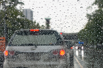 Raindrops cling to the windshield of a car while driving on the road.