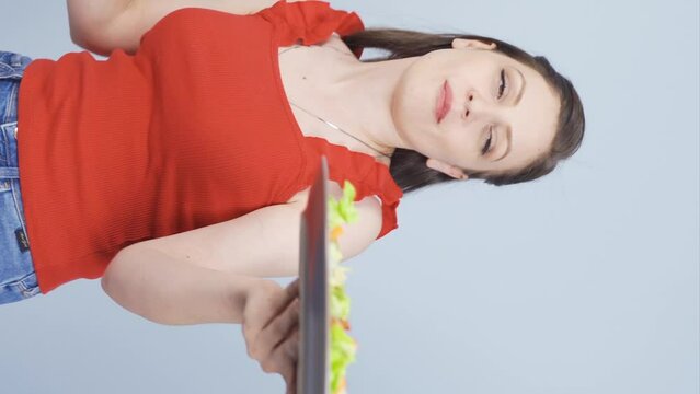 Vertical video of A person who diets and eats healthily. She eats salad and dances.