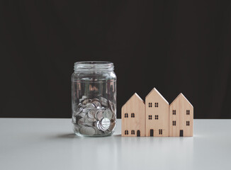  coins in jug glass with wood house model. Balance savings Interest and investment Concept. Business planning and financial management.