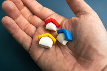 Colored houses in the hand palm. Consider different housing options. Finding the perfect one. Buy a house. Real estate investment. Property value appraisal. Make a deal. Property Insurance.