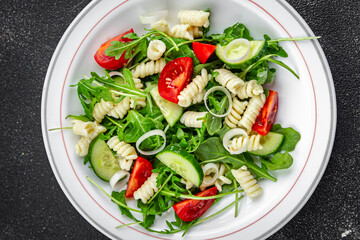 pasta salad fusilli pasta, cucumber, tomato, green lettuce, onion eating appetizer meal food snack on the table copy space food background rustic top view