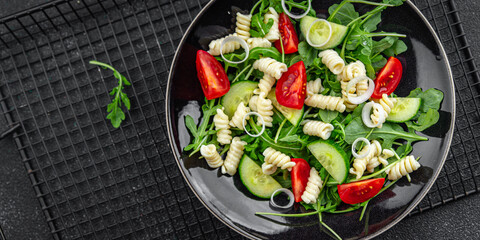 pasta salad fusilli pasta, cucumber, tomato, green lettuce, onion eating appetizer meal food snack on the table copy space food background rustic top view