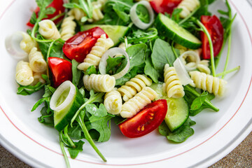 pasta salad fusilli pasta, cucumber, tomato, green lettuce, onion eating appetizer meal food snack on the table copy space food background rustic top view