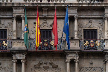 Vista del balcón del ayuntamiento de Pamplona donde se lanza el chupinazo de las fiestas de San Fermin con las banderas oficiales. - obrazy, fototapety, plakaty