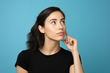 Portrait of a beautiful brunette woman thinking. Isolated on a plain blue background. Generative AI.