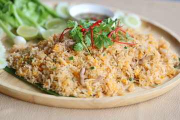 Top view of pork fried rice with egg and sliced ​​spring oniontopped with coriander leaves and sliced ​​red chili. Close up delicious home made fried rice served on wooden plate with fresh vegetables
