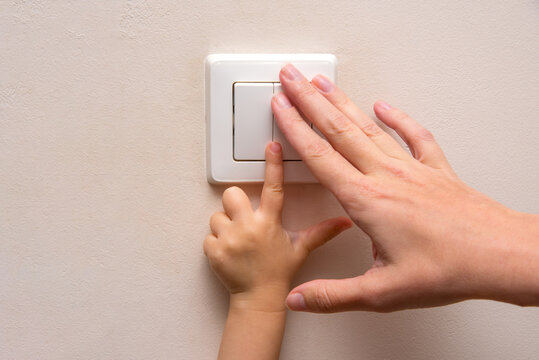 Mom teaches her kid to turn on the light inside the house or room.