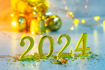 New Year holiday background. Golden numbers 2024 with a New Year tree and bright glowing lights.