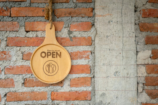Open sign of the food restaurant or cafe which is made from wooden material, hanging on the brickwall. Sign and symbol object photo, close-up.