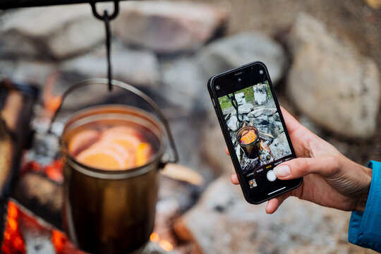 Taking pictures on the phone of a pot on the fire, a female hand with a smartphone filming the food cooking process, art photography, food photo.