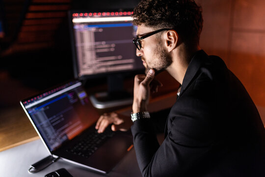 Young man writes program code on a computer, programmer work in home office.