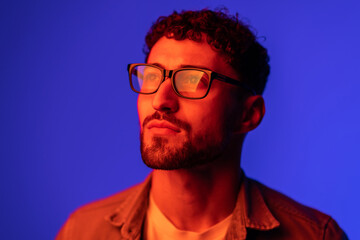 Obraz premium Portrait of young handsome man looking away against gradient purple background in neon light.