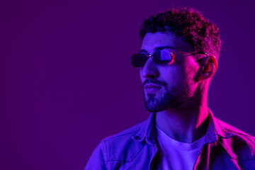 Neon light portrait of serious man beard in sunglasses