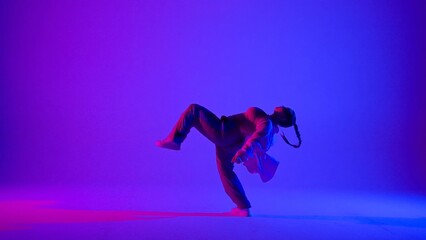 Attractive woman dancing jazz-funk on pink and blue neon background in a studio. Modern dynamic and energetic dance choreography. Full length.