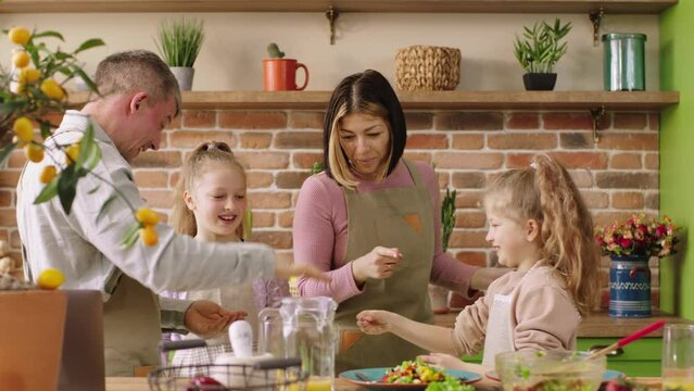 Excited Caucasian family parents and two kids girls happy playing rock paper scissors before start to cook the dinner together at the rustic kitchen island