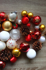 Pine cones and red, golden and white Christmas ornaments on wooden background. Top view.