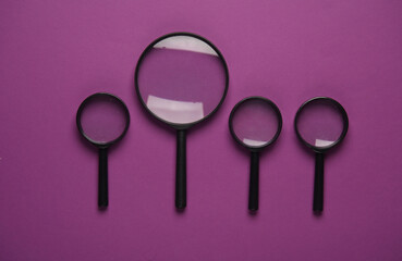 Magnifiers on purple background. Top view