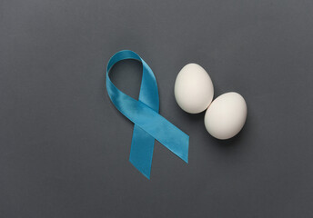 Blue ribbon symbolizing support of men and eggs on dark background. Blue november prostate cancer...