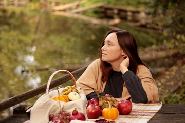 picnic by the lake, young woman, fruits, pie and pumpkins on the table