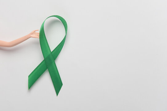 Dool hand with Green awareness ribbon on white background. World mental health day concept