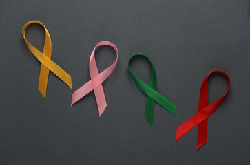 Red, pink, yellow, green awareness ribbons on dark background